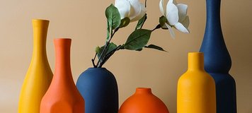Collection de vases décoratifs en céramique aux teintes orange, jaune et bleu marine, avec fleurs blanches artificielles, sur fond beige - Benigna Nunes Pinterest