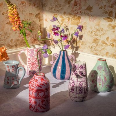 Collection de vases et pichets en céramique colorée avec motifs floraux, exposés dans un intérieur vintage à la lumière du soleil Source - alex Pinterest