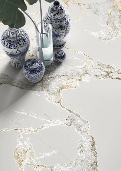 Gros plan sur céramique effet marbre blanc et doré de la collection Athens, chez Céramique l’Entrepôt, accompagnée de vases décoratifs en porcelaine bleue et blanche