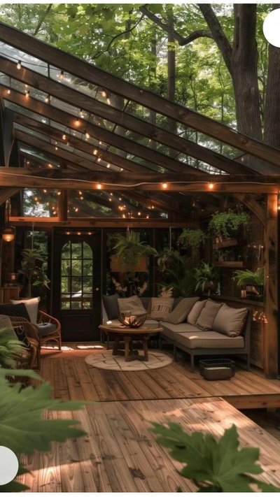 Terrasse en bois sous verrière avec guirlandes lumineuses Source - Breyan Knutson Pinterest Terrasse en bois sous verrière avec guirlandes lumineuses, canapé confortable et plantes suspendues, créant une ambiance chaleureuse et naturelle au cœur de la forêt Source - Breyan Knutson Pinterest