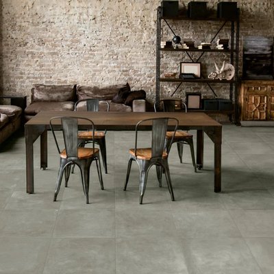 Salle à manger au style industriel avec mur de briques et céramique effet béton gris de la collection Cerabeton, chez Céramique l’Entrepôt