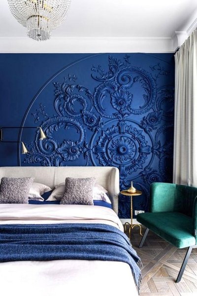 Chambre moderne avec un mur bleu profond orné de moulures florales en relief, lit rembourré beige et fauteuil vert émeraude Source - Luxury Living Rooms Ideas Pinterest