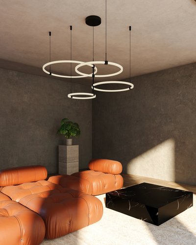 Chandelier suspendu moderne Bruni de chez Luminaires & Cie composé de quatre anneaux lumineux noirs à DEL, flottant au plafond d’un salon minimaliste avec murs en béton, canapé modulaire en cuir cognac, table basse en marbre noir et plante verte sur piédestal