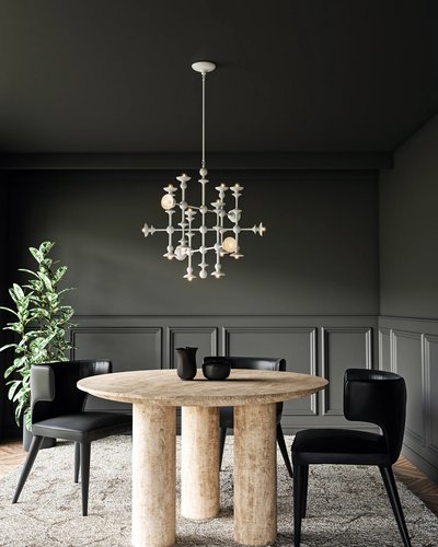 Chandelier Cadence suspendu dans une salle à manger moderne et sombre, au-dessus d’une table ronde en bois brut entourée de chaises noires élégantes, avec un mur mouluré gris charbon et un tapis texturé au sol