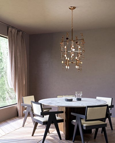 Salle à manger moderne avec une table ronde en marbre, entourée de chaises au design géométrique, surmontée d’un chandelier doré Yukari de chez Luminaires & Cie orné de détails suspendus, créant une ambiance élégante et artistique