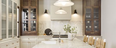 Cuisine haut de gamme au style classique chic avec armoires vitrées brun foncé, dosseret et comptoir en marbre, robinet rétro et chaises en rotin, Cuisine haut de gamme au style classique chic avec armoires vitrées brun foncé, dosseret et comptoir en marbre, robinet rétro et chaises en rotin, signée Armoires Cuisines Action