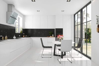 Cuisine lumineuse et minimaliste signée Onivo, avec armoires blanches sans poignées, dosseret et comptoir en granite noir, coin-repas avec table ronde blanche et chaises modernes, grandes fenêtres pleine hauteur avec vue sur jardin