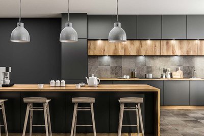 Cuisine moderne noire signée Rénovilla avec armoires mates, accents de bois naturel, comptoir et îlot en bois clair, dosseret en céramique effet béton, luminaires suspendus style industriel et tabourets rustiques