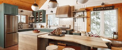 Cuisine chaleureuse au style champêtre avec armoires vert pin, comptoirs blancs, dosseret en tuiles métro, îlot en bois brut et éléments décoratifs rustiques, réalisée par Armoires Cuisines Action