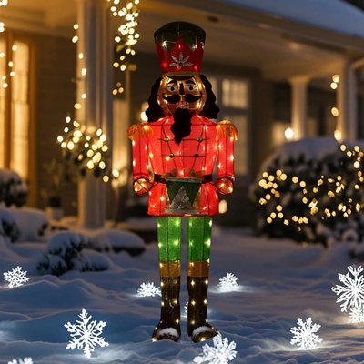 Casse-noisette lumineux décoratif de Noël en rouge, vert et doré, placé sur la neige devant une maison illuminée pour les fêtes - Wayfair
