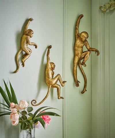 Trois sculptures murales dorées de singes accrochées à un mur vert pâle, apportant une touche ludique et originale à la décoration intérieure Source - Joe Browns Pinterest