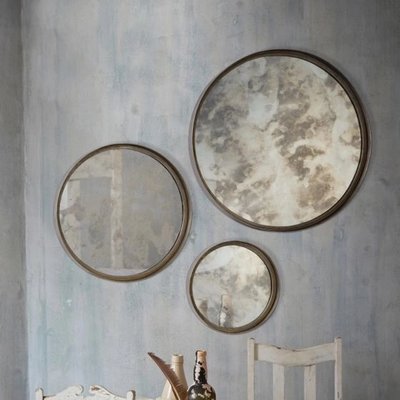 Ensemble de 3 miroirs Shire chez Linen Chest – Trio de miroirs ronds vieillis à cadre métallique, disposés en composition murale décorative dans une pièce au style rustique et bohème.