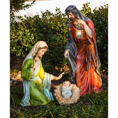 Scène de la Nativité en extérieur représentant Marie, Joseph avec une lanterne, et l'Enfant Jésus dans une mangeoire, entourés de verdure - Wayfair