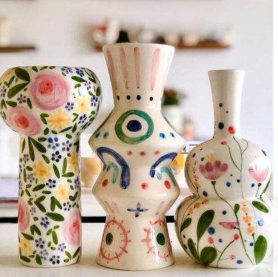 Trois vases en céramique blanche aux formes originales, décorés de motifs floraux et abstraits multicolores, posés sur une surface blanche Source - Fieke Paulus Pinterest