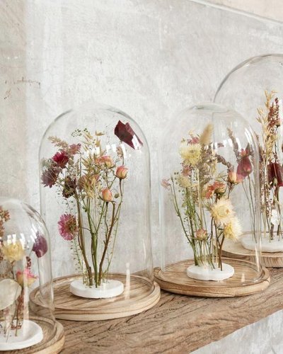 Arrangement de fleurs séchées sous des cloches de verre posées sur des socles en bois, dans un décor épuré et naturel Source - Pinterest
