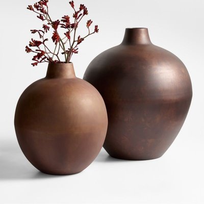 Deux grands vases décoratifs en céramique brun mat, l'un orné de fines branches rouges, posés sur un fond blanc minimaliste Source - Heidi Koch Pinterest
