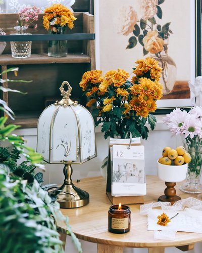 Photo par Dekorfine Lampe de table en laiton avec abat-jour en verre décoré de fleurs, posée sur une table en bois entourée de bouquets, image Pinterest