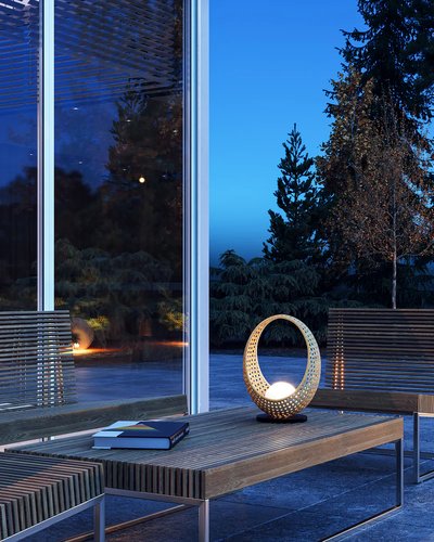 Lampe de table en forme de croissant ajouré avec lumière intégrée, posée sur une table basse en bois dans un espace extérieur moderne, photo par Luminaires & cie