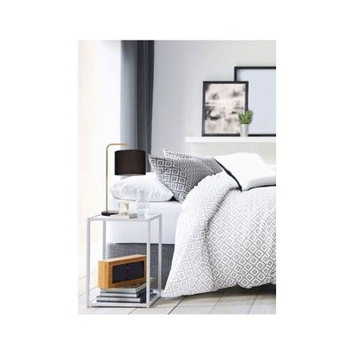 Lampe de table moderne avec abat-jour noir et structure dorée, posée sur une table de chevet métallique dans une chambre au décor scandinave avec literie à motifs géométriques gris et blancs, image provenant de Royaume Luminaire
