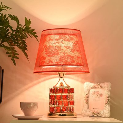 Lampe de table avec pied doré orné de carreaux rouges et abat-jour en tissu rouge à motifs floraux