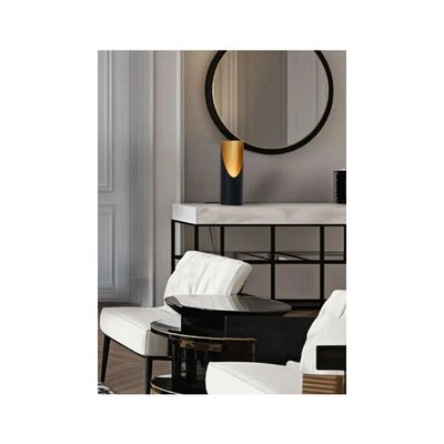 Lampe de table design noir et doré au style contemporain, posée sur une console en marbre blanc dans un salon élégant avec fauteuils blancs et miroir rond mural, image provenant de Royaume Luminaire