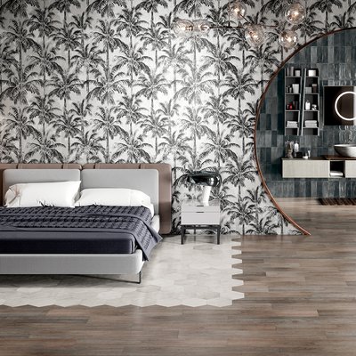 Chambre à coucher contemporaine avec revêtement mural tropical en noir et blanc représentant des palmiers, sol en carrelage hexagonal blanc fusionné avec un plancher effet bois, et grande ouverture en miroir arrondi donnant sur une salle de bain moderne aux tuiles bleu foncé par Déco Surfaces.