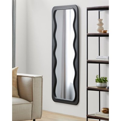 Miroir mural rectangulaire à cadre ondulé noir de Lovaco, installé dans un salon moderne avec canapé beige et étagère décorative.