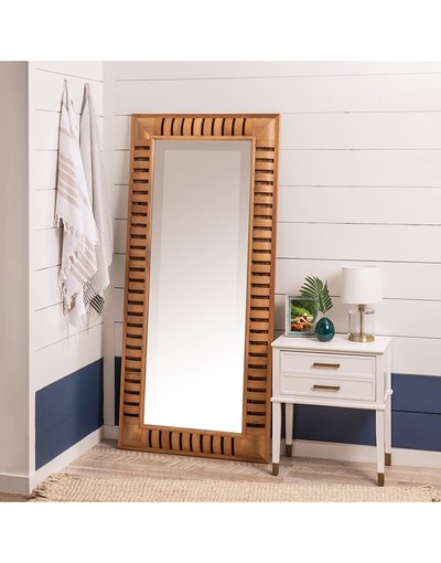 Grand miroir rectangulaire avec cadre en bois ajouré de chez Ô Miroir, appuyé contre un mur blanc et bleu dans une pièce au style côtier.