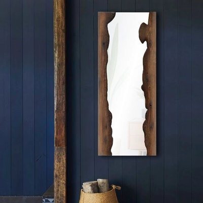 Miroir Connix chez Linen Chest – Miroir mural rectangulaire avec cadre en bois brut aux bords irréguliers, accroché sur un mur bleu foncé pour un style rustique et naturel.