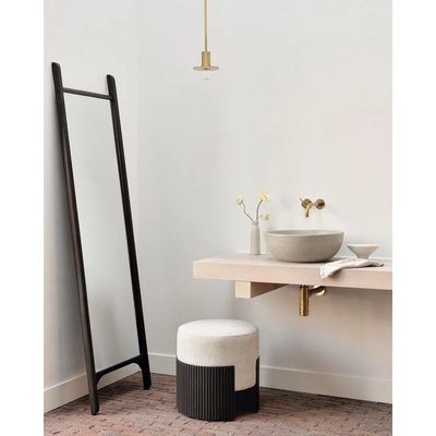 Miroir sur pied minimaliste avec cadre noir de Lovaco, placé dans une salle de bain moderne aux accents dorés et décor épuré.