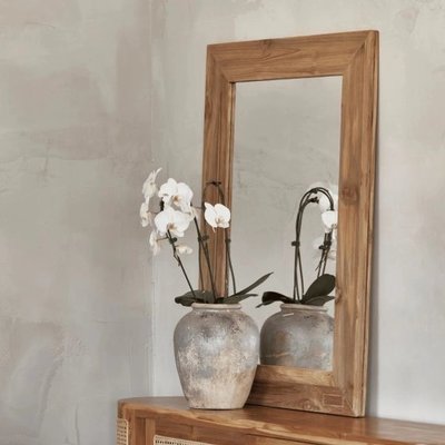 Miroir en teck recyclé chez Linen Chest – Miroir rectangulaire à cadre en bois de teck naturel recyclé, posé sur une console rustique avec vase en céramique et orchidées blanches.