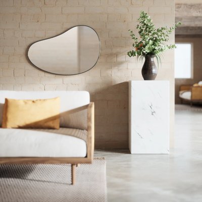 Miroir mural organique à cadre noir de chez Kozy, accroché sur un mur en brique dans un salon lumineux au style naturel et épuré.