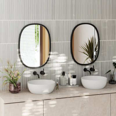 Miroir mural ovale Hub de Umbra de chez Brick – Ensemble de deux miroirs ovales noirs modernes au-dessus d’un double lavabo sur comptoir en pierre, créant une salle de bain contemporaine et élégante.