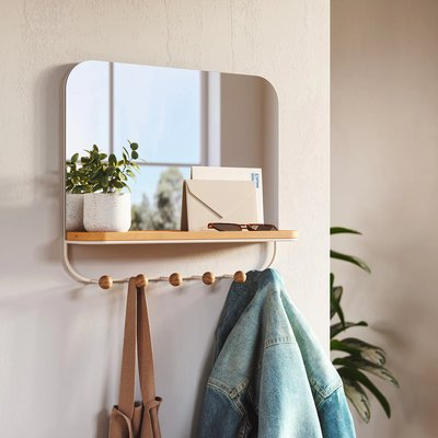 Miroir mural rectangulaire arrondi avec tablette et crochets en bois de chez Kozy, installé dans une entrée chaleureuse avec plante et vestes accrochées.