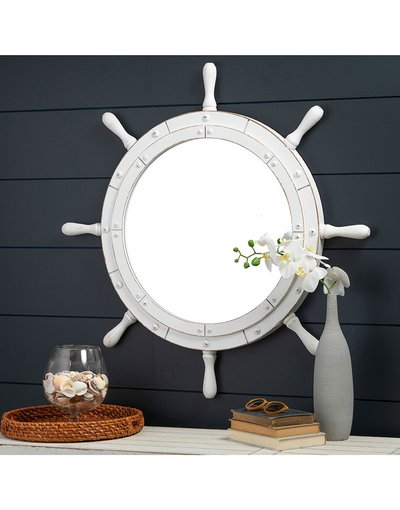 Miroir rond style gouvernail blanc de chez Ô Miroir, accroché sur un mur bleu marine au-dessus d’une console décorative à thème nautique.