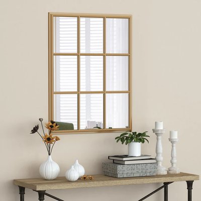 Miroir Trepion de chez Brick – Miroir mural rectangulaire avec encadrement doré en grille rappelant une fenêtre, installé au-dessus d’une console décorée de vases et bougeoirs élégants.