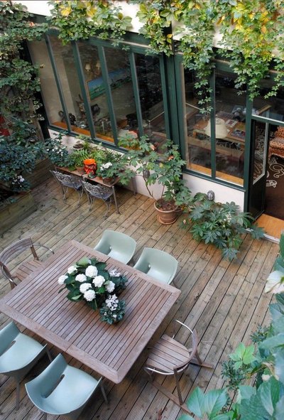 Terrasse extérieure en bois entourée de plantes grimpantes Source - Mon Jardin Ma Maison Pinterest Terrasse extérieure en bois entourée de plantes grimpantes, avec grande table à manger et chaises modernes, créant un espace verdoyant et convivial Source - Mon Jardin Ma Maison Pinterest