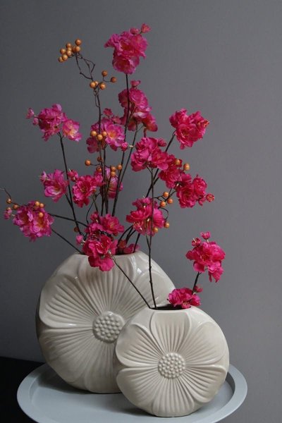 Deux vases en céramique beige en forme de fleur, ornés de branches fleuries de fleurs roses éclatantes et de baies orangées, sur fond gris Source - Mrsjoão_ Pinterest