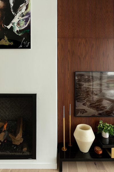 Mur décoratif en lattes de bois verticales de style moderne mettant en valeur un coin salon élégant avec foyer au gaz encastré, œuvres d'art contemporaines, accessoires dorés et vase design, parfait pour une ambiance chaleureuse et raffinée de chez Mur Tendance.