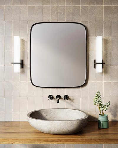 Salle de bain épurée avec lavabo en pierre ovale, mur de céramique beige, miroir carré à coins arrondis et deux appliques murales modernes à lumière blanche verticale de Luminaires & Cie
