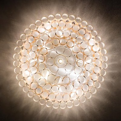 Vue en contre-plongée du plafonnier Odeon de Slamp, composé d’anneaux dorés illuminés créant un effet de halo lumineux sculptural – Maison du Luminaire