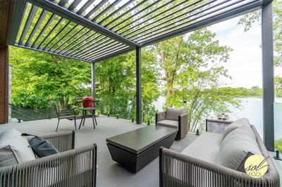 Terrasse au bord de l’eau avec pergola bioclimatique de Auvents Valleyfield et mobilier extérieur moderne