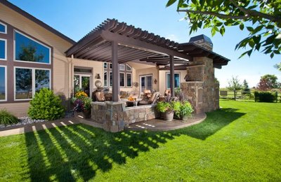 Pergola en bois attenante à une maison contemporaine avec piliers en pierre et espace lounge extérieur sur pelouse verte, provenant de Decoist.