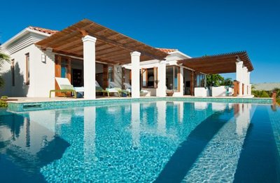 Maison contemporaine avec pergola en bois et grande piscine turquoise sous un ciel bleu éclatant, provenant de Decoist.