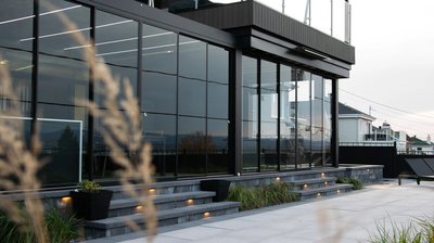 Mur de verre coulissant avec cadre en aluminium noir installé sur une terrasse moderne, projet Pergolas Signature