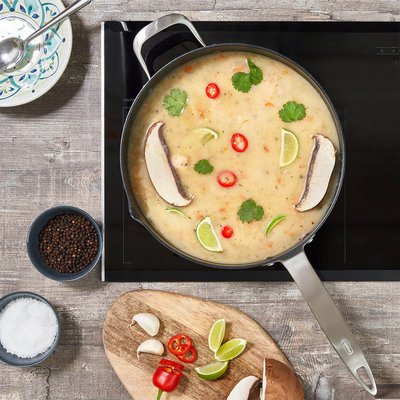 Poêle à frire antiadhésive Zyliss Ultimate Pro de 11 pouces de chez Eugène Allard sur une plaque à induction, contenant une soupe asiatique garnie de champignons, lime, piments rouges et coriandre