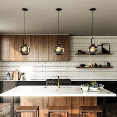 Cuisine moderne avec îlot central en bois et quartz blanc, éclairée par trois suspensions rondes en verre fumé de la collection Soji Round chez Maison du Luminaire