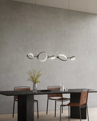 Suspension linéaire Serif de chez Luminaires & Cie au design sculptural composée d’anneaux lumineux suspendus au-dessus d’une table rectangulaire noire, accompagnée de chaises en cuir brun, dans une salle à manger moderne au décor minimaliste avec mur en béton gris