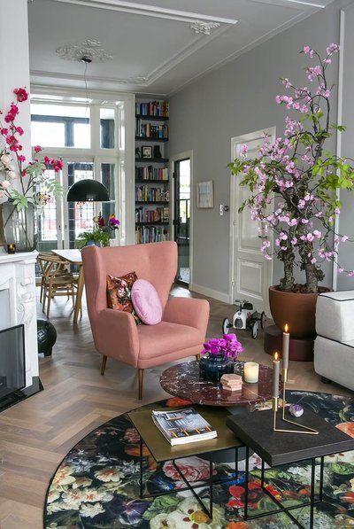 Salon élégant avec fauteuil rose Source - Wiesje Pinterest Salon élégant avec fauteuil rose, table basse design, tapis floral, grandes plantes en pot et détails décoratifs aux teintes printanières Source - Wiesje Pinterest