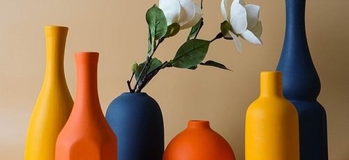 Collection de vases décoratifs en céramique aux teintes orange, jaune et bleu marine, avec fleurs blanches artificielles, sur fond beige - Benigna Nunes Pinterest